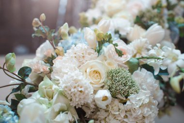 Güller, ortancalar ve diğer çiçeklerin yer aldığı güzel beyaz bir çiçek aranjmanı. Düğün dekorasyonu için mükemmel. Zarafet, romantizm ve kutlama temaları için idealdir. Yüksek kaliteli çiçek sergilenir.