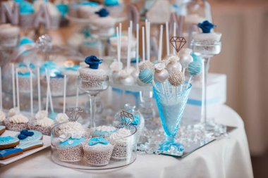 Mavi ve beyaz temalı kekler, kekler ve kurabiyelerin yer aldığı şık bir tatlı gösterisi. Düğünler, bebek partileri ve lüks etkinlikler için mükemmel. Yüksek kalite ve görsel olarak çarpıcı bir düzenek..