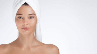 Kafasına havlu sarılmış genç bir kadın stüdyo ortamında güven içinde poz veriyor. Güzellik, cilt bakımı ve refah kavramları için ideal. Doğal güzellik ve kendine bakımı vurguluyorlar.. 
