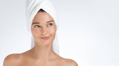 Güzel, genç bir kadın. Parlak bir teni ve beyaz bir havlusu var. Kafasına sarılmış, hafifçe gülümsüyor. Cilt bakımı, güzellik, sağlık reklamları ve promosyonlar için mükemmel.. 