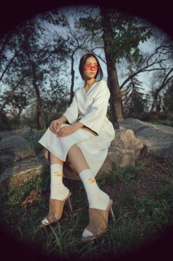 Modern Asyalı kadın kendine güvenen beyaz bir elbise, eğlenceli resimli çoraplar ve kırmızı gözlüklü sandaletler giyer. Moda başyazıları, ilginç trendler ve benzersiz kişisel tarzlar için harikadır.