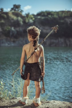 Caveman, taş baltalı erkeksi adam ve nehir kenarında yay avı. Tarih öncesi kabile çocuğu doğada açık havada. Genç tüylü ve kirli vahşi, savaşçı ve avcı. Hayvan derisinde ilkel buz devri adamı