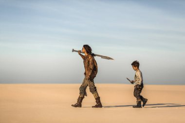 Kıyametten sonraki kadın, elinde kılıç, elinde bıçak olan çocuk engin çölde yürüyor. Yüksek kaliteli bilim kurgu hayatta kalma konsepti sinematik hikaye anlatımı ve fantezi tanıtımları için mükemmeldir..