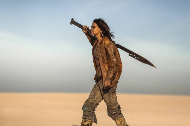 Huzursuz, post-apokaliptik kıyafetli bir kadın çölde tek başına yürüyor, elinde büyük bir kılıçla. Yüksek kaliteli bilim kurgu hayatta kalma kavramı fantezi tanıtımı, film afişleri ve aksiyon sanatı için idealdir..