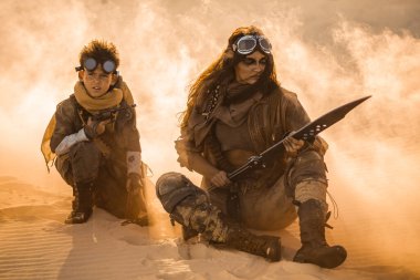 Kıyametten sonra kılıçlı bir kadın ve silahlı bir çocuk kum fırtınasında diz çöker. Kavramsal bilim kurgu hayatta kalma imajı, film posterleri, tanıtım reklamları veya fantezi aksiyon öyküleri için mükemmel..