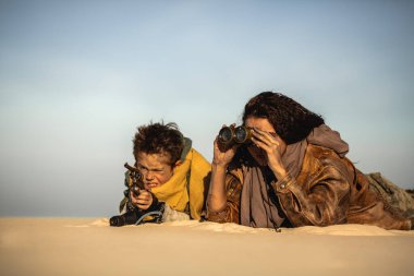 Dürbünlü bir kadın ve çölde yüzen tüfekli bir çocuk. Eylem için yüksek kaliteli post-apokaliptik hayatta kalma konsepti, bilim kurgu tanıtımları, film posterleri ve macera görselleri.
