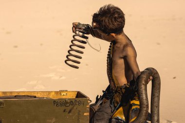 Hayatta kalma ekipmanlı tişörtsüz çocuk çölde yeşil bir askeri çantanın içinde bulunan yayı inceliyor. Yüksek kaliteli bilim kurgu fantezi sahnesi sinematik hikaye anlatımı ve leş yiyen temalar için idealdir..