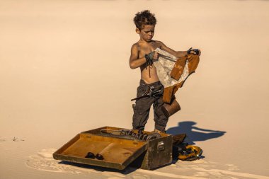 Kıyametten sonra giydiği gömleksiz çocuk çöldeki açık davadan ceketini inceliyor. Yüksek kaliteli bilim kurgu konsepti imajı. Fantezi hikaye anlatımı ve sinematik tanıtım içeriği için mükemmel..