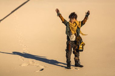 Kıyamet sonrası kıyafetli genç, parlak çölde teslim olmak üzere ellerini kaldırdı. Yüksek kaliteli bilim kurgu hayatta kalma görüntüsü sinematik hikaye anlatma, dramatik tanıtım ve fantezi konsepti sanatı için mükemmel..