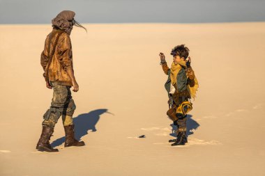 Bilim kurgu çöl manzarasında genç bir çocuk silahlı bir kadının önünde teslim olarak ellerini kaldırır. Fantezi hikayeleri, dramatik tanıtımlar ve yüksek kalitede aksiyon güdümlü görsel kavramlar için mükemmel..