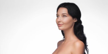 Kusursuz derisi ve koyu renk saçları olan, sakince bakışlarını kaçıran beyaz bir kadının yüksek kalite portresi. Cilt bakımı, sağlık ve kozmetik markalaşma için kavramsal görüntü.