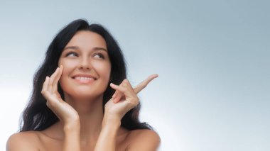 Beyaz tenli, beyaz tenli, uzun siyah saçlı, gülümseyen bir kadın. Ürün yerleştirme, güzellik tanıtımı, reklamcılık veya cilt bakımı ve kozmetik tasarım kullanımı için harika.