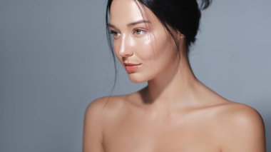 Çıplak omuzları ve ışıl ışıl cildi olan, yumuşak ışıkta yakalanmış bir kadının huzurlu portresi. Onun barışçıl ifadesi ve parlayan teni bu görüntüyü cilt bakımına, güzelliğe ve sağlığa ideal kılıyor.