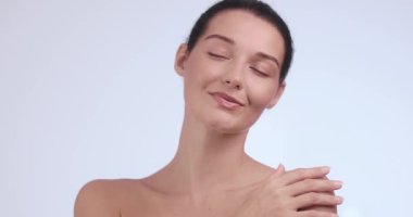 Zarif kadın omuzlarını okşar ve köprücük kemiğini yumuşak bir dokunuşla okşar, gözleri huzur içinde kapalıdır. Güzellik, cilt bakımı, sağlık, kişisel bakım ve kadınsı zarafet için ideal..