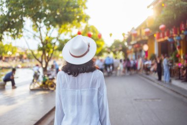 Kafkasyalı turist gün batımında Vietnam 'da Hoi An' da yürüyor. Fenerler ve eski mimari çizgiler hayat dolu caddede. Seyahat reklamları, yaşam tarzı blogları ve promosyon görselleri için mükemmel..