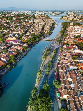 Hoi An, Vietnam 'ın çarpıcı hava manzarası, sergilenen kiremitli çatılar, dolambaçlı nehir ve ikonik köprü. Kültürel seyahat promosyonları, Asya blogları ve turizm pazarlama görselleri için ideal.