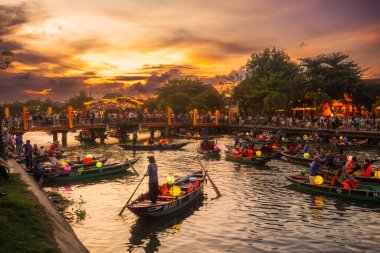 Renkli fener tekneleri ve kalabalığı, Vietnam 'ın Hoi An şehrinde altın günbatımında toplanıyor. Turizm kampanyaları, editoryal görseller ve yüksek kaliteli promosyonlar için mükemmel bir kültürel seyahat imajı..