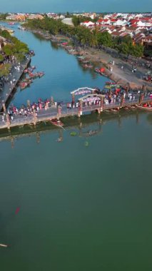 Hava aracı Hoi An, Vietnam 'daki ikonik Fener Köprüsü' nden uzaklaşıyor. Kamera yükselir ve geri çekilir, nehir kenarındaki yaşamı, tekneleri, çatıları ve canlı eski kasabayı gözler önüne serer. Seyahat için ideal