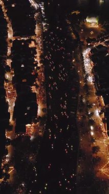 Hoi An nehrinin parlayan fener tekneleriyle dolu havadan çekilmiş gece görüntüleri. Şehrin her iki yakasında da caddeler aydınlanıyor. Kültürel seyahat, gece hayatı ve Güneydoğu Asya promosyon içeriği için mükemmel. 