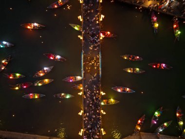 Hoi An 'ın parlayan köprüsünün ve gece vakti kalabalık ve şenlik enerjisiyle dolu renkli fener teknelerinin çarpıcı hava perspektifi. Seyahat, kültür ve etkinlik promosyonları için mükemmel..