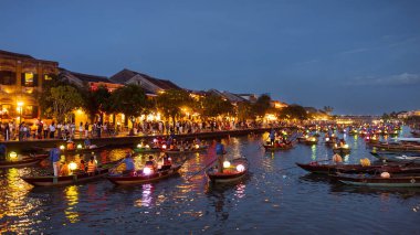 Fener ışığında yakılan tekneler Hoi An, Vietnam 'da turistlerin parlayan rıhtımda kuyruk oluşturduğu nehirde dolaşıyorlar. Seyahat tanıtımları, turizm afişleri ya da kültür odaklı reklamlar için mükemmel zengin, şenlikli bir sahne..