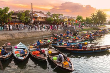 Renkli geleneksel tekneler Hoi An nehri boyunca demirledi, Vietnam 'da altın günbatımında. Canlı ve kültürel sahne seyahat promosyonları, turizm reklamları veya Güneydoğu Asya görselleri için mükemmel.