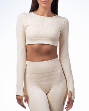 Fiyakalı, krem rengi bir üst ve tayt giyen sağlıklı bir kadının kırpılmış görüntüsü. Moda, giysi markası, vücut bakımı ya da sağlık kampanyaları için ideal bir stüdyo çekimi..