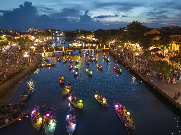Hoi An, Vietnam 'ın insansız hava aracı tarafından ele geçirilmesi, gece fener ışığında nehirde süzülen tekneler ve canlı sokak ışıkları. Turizm reklamları, seyahat blogları ve kültür makaleleri için ideal.
