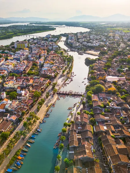 Hoi An, Vietnam 'ın, ikonik nehri, ahşap botları ve turizm pazarlaması, seyahat blogları ve kültürel makaleler için mükemmel döşenmiş çatıları gösteren altın saat görüntüsü..