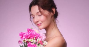 Güzel beyaz bir kadın pembe ve beyaz bir buketi ağır çekimde kucaklıyor. Romantik kampanyalar, cilt bakımı ve çiçek temalı güzellik reklamları için ideal..