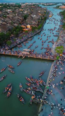 Aşağıdaki insansız hava aracı görüntülerinde Hoi An, Vietnam 'daki nehrin kıyısında ve köprünün üzerinde düzinelerce fener yanan ahşap botlar görülüyor. Seyahat, kültür ve turizm projeleri için mükemmel..