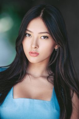 Parlak tenli, doğal makyajlı, göz kamaştırıcı Asyalı kadın yakın plan bir moda portresiyle dışarıda poz veriyor. Cilt bakımı, güzellik, tanıtım, lüks editörler ve reklam kullanımı için ideal.