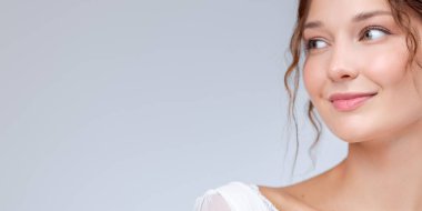 Işıl ışıl cildi ve yumuşak dudakları olan gülümseyen ve yana bakan bir kadının yakın çekimi. Cilt bakımı, yüz bakımı, kozmetik markalar ve sağlık ve sağlık tasvirleri için mükemmel..