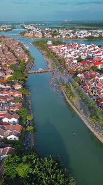Hoi An, Vietnam 'daki Thu Bon nehrinin üzerinde sorunsuz bir şekilde dönen insansız hava aracının hava görüntüleri. Videoda kiremitli çatılar, palmiye çizgili yollar ve antik kıyı şeridi boyunca bulunan tekneler görülüyor. Turizm için harika.