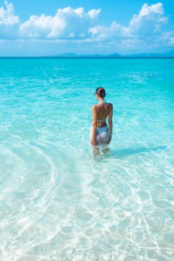 Tayland, Krabi yakınlarındaki Phi Phi Takımadası 'nın bir parçası olan Bambu Adası' nın el değmemiş turkuaz sularında duran genç bir kadının çarpıcı görüntüsü..
