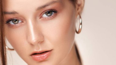 Açık tenli, parlak dudaklı ve altın halka küpeli genç bir kadının göz kamaştırıcı yakın çekimi. Lüks moda, kozmetik, cilt bakımı ya da güzellik kampanyaları için ideal..