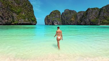 Tayland 'da Maya Körfezi' nde bikinili bir kadının turkuaz suya doğru yürüdüğünü gördüm. Güneydoğu Asya 'da tropikal seyahat, lüks tatil beldesi, sağlık ve tatil tanıtım için mükemmel..