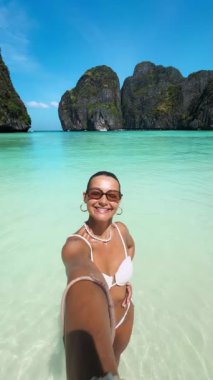 Beyaz bikinili neşeli kadın Tayland 'ın Phi Phi Adaları' ndaki Maya Körfezi 'nin çarpıcı turkuaz sularında selfie çekiyor. Etkilenen, seyahat, yaz ve yaşam tarzı içeriği için mükemmel bir kavram.
