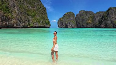Maya Bay, Krabi 'de beyaz bikinili şık bir Kafkas modelinin lüks, yavaş çekim görüntüleri. Turkuaz su ve kireçtaşı kayalıkları yaz için mükemmel bir tanıtım zemini oluşturuyor..