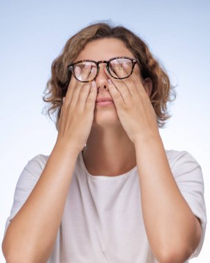 Gözlük takıp gözlerini ovuşturan, beyaz arka planda izole edilmiş, göz ağrısı çeken yorgun Avrupalı genç bir adam. Yorgunluk, aşırı çalışma, stres ve sağlık hizmetleri. Adam baş ağrısı veya rahatsızlıktan muzdarip.