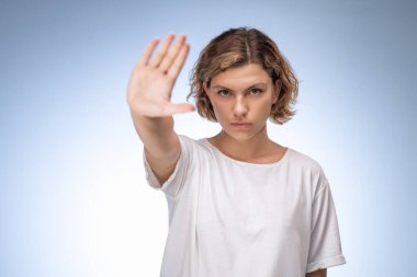 Kararlı kadın avucunu dışa doğru uzatıyor güçlü bir dur hareketiyle, yoğun bir şekilde ileri bakıyor. Protesto, sınır belirleme, güvenlik farkındalığı veya sosyal direniş kampanyaları için ideal.