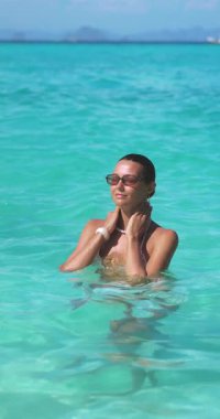 Beyaz bikinili beyaz kadın Maldivler 'de sakin denizin tadını çıkarıyor. Huzurlu, zarif bir an güzellik, yaşam tarzı, seyahat ve cilt tanıtımı için mükemmel. Yüksek kaliteli tropikal video.