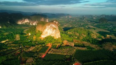 Krabi kireçtaşı tepeleri ve yemyeşil tarım arazileri üzerinde drone daireler çizerken hava manzarasını yavaş çekimde süpürüyorlar. Büyüleyici altın ışık ve arazi seyahat veya sinematik kullanım için mükemmel..