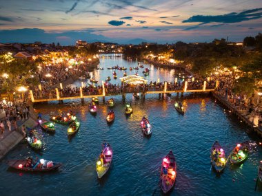Hoi An 'daki ikonik köprü, gece feneri festivali sırasında ışıldıyor. Canlı kalabalıklar ve renkli tekneler, afişler ve başyazılar için ideal bir seyahat ve kültür görüntüsü..
