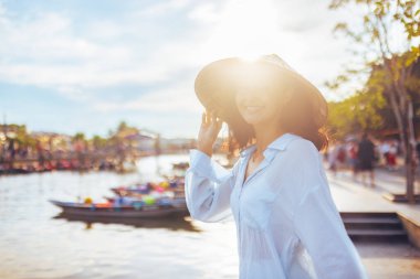 Hoi An 'da, Vietnam' da yaşam tarzı, kültür, seyahat ve editoryal tanıtım için ideal ışık altında gülümseyen şapkasız genç bir kadın yumuşak ve egzotik bir cazibe yakalıyor..