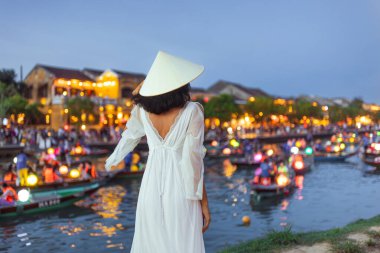 Geleneksel konik şapkalı Asyalı kadının Hoi An, Vietnam 'da fener ışığında yanan teknelere bakışını. Seyahat, kültür, romantizm, tatil, turizm ve yaşam tarzı kavramı.