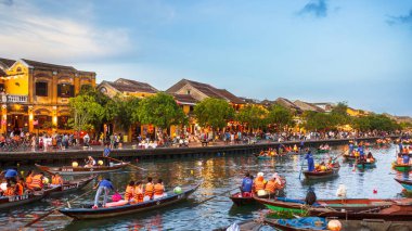 Vietnam, Hoi An 'daki Thu Bon Nehri' nde hareketli bir akşam. Geleneksel teknelerdeki turistler kalabalık Antik Şehir rıhtımının manzarasının tadını çıkarıyorlar. Seyahat ve turizm için yüksek kaliteli bir tanıtım