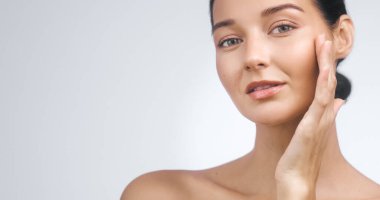 Yüzüne dokunan güzel beyaz kadın doğal cilt bakım konsepti sergiliyor. Kozmetik reklam materyalleri için mükemmel ciltli kaliteli bir stüdyo portresi.. 