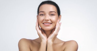 Yüzüne gülümseyen ve nazikçe dokunan parlak, pürüzsüz ciltli güzel bir kadın cilt bakımını, güzelliğini ve sağlığını sembolize ediyor. Kozmetik ve kişisel bakım promosyonları için mükemmel.. 