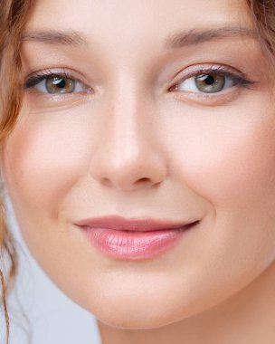 Kusursuz cildi, parlak dudakları ve açık renk makyajı olan gülümseyen bir kadının yumuşak bir yakın çekimi. Cilt bakımı, güzellik yaşam tarzı içeriği ve minimalist kozmetik reklamları için mükemmel..